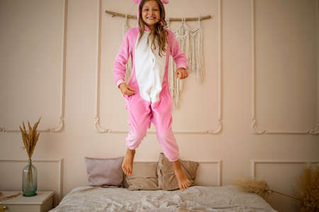 Portrait Of Happy Cute Little Girl in a funny jacket In Bedroomの写真素材