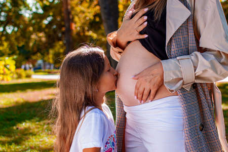 Pregnant Mother With Little Daughter In Autumn Park. Family Waiting New Baby.