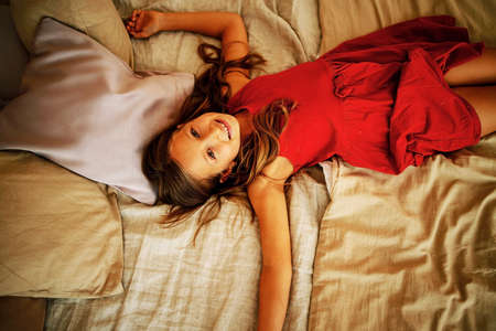 Happy Cute Little Girl Lying In Bedの写真素材