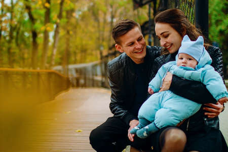 young family and newborn son posing for the camera in autumn park.の写真素材