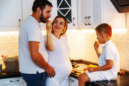The family is having breakfast on the kitchen and cutting oranges at the table.の写真素材