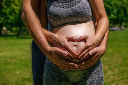couple creating a love heart with their hands - pregnancy.
