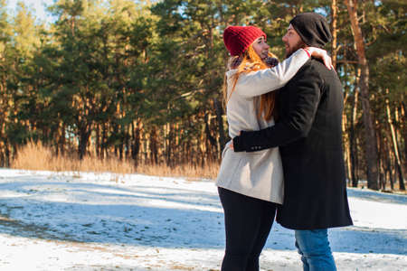 Couple in a winter forest and frozen lake. Young lovers in winter jackets laugh.の写真素材