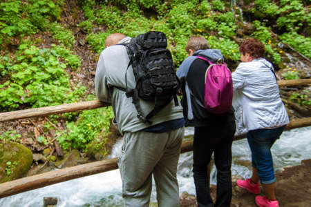Rear view of travelers with backpacks are standing in the background of waterfalls.