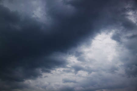 The sun's rays make their way through the dark clouds in the sky. Gloomy weather before a thunderstormの写真素材