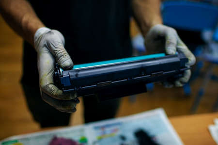 hands working refilling printer cartridge. The Master Holds The Disassembled Laser Printer...