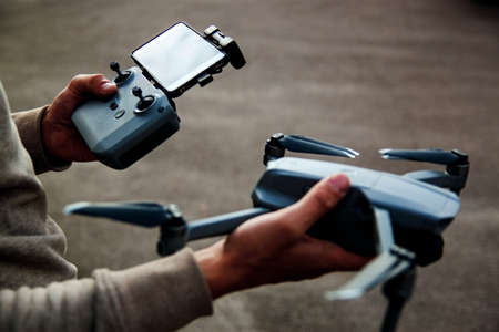 The UAV drone and photographer man hands close-up.drone copter flying with digital camera. Flying camera take a photo and video.の写真素材