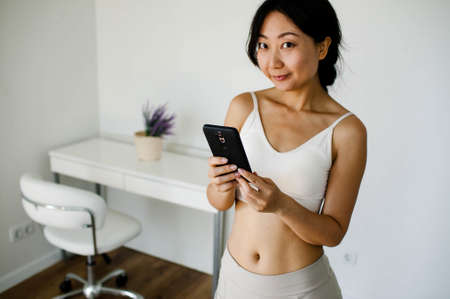 Young Fit Asian Girl In Sportswear Does Sport Exercises At Home.の写真素材