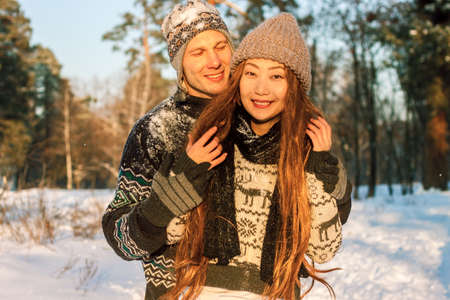 Beautiful mixed race international couple holding snowflakes and smiling in the park in the winter...