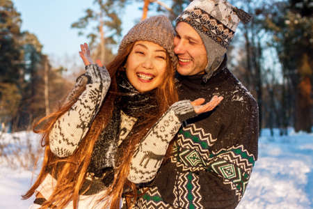 Beautiful mixed race international couple holding snowflakes and smiling in the park in the winter on the snow.の写真素材