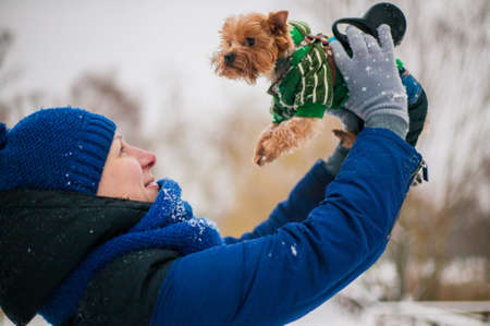 Girl holding a dog in the park in the winter on snow. care for a dog in the cold season.の写真素材