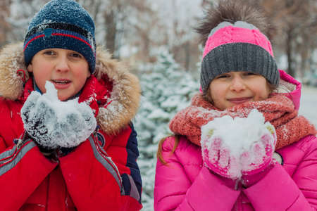 Happy cheerful family with children and dog having fun on snow in park in winter.の写真素材