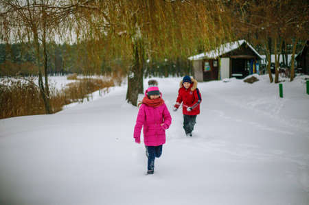 Happy cheerful family with children and dog having fun on snow in park in winter.の写真素材