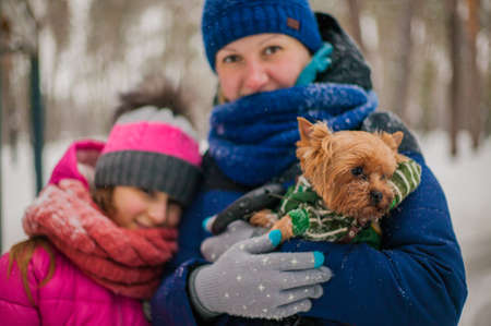 Happy cheerful family with children and dog having fun on snow in park in winter.の写真素材