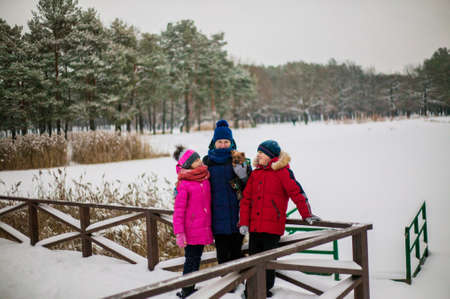 Happy cheerful family with children and dog having fun on snow in park in winter.の写真素材