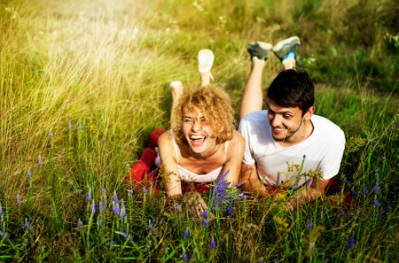 Young loving couple enjoying nature, holding hands and walking on the field with lavender. Beautiful people on nature in summer at sunset.の写真素材