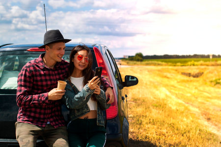 Young couple traveling by car stopping to drink coffeeの写真素材