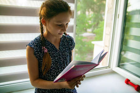 Story concept. Happy girl read interesting story. Little child ejoy bedtime story in bed. Good night story.の写真素材