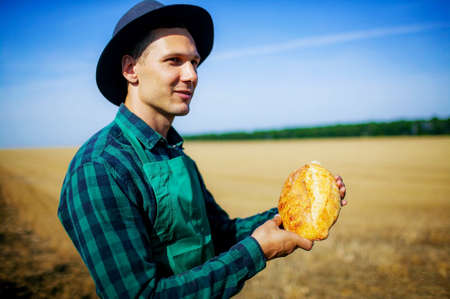 Man Farmer Holding Homemade Rustic Wheat Bread In Hands In A Wheat Field.