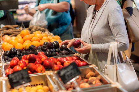 woman shopping for fruits and vegetables in produce department of a grocery store / supermarket