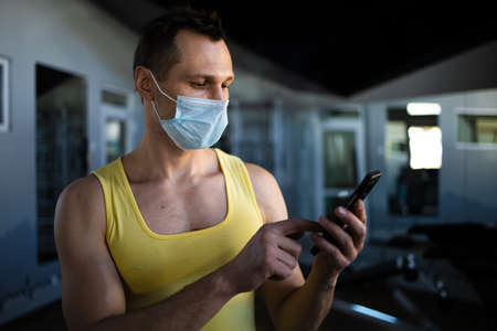Profile View Of Young Man With Mask Using Phone At Gymの写真素材