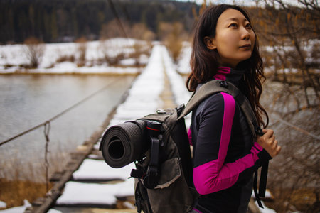 Woman Tourist With A Backpack Walks On A Bridge In The Winter Forest.の写真素材