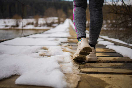 Close-up of legs in white sneakers on the road In Winter Forest.の写真素材