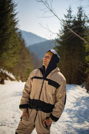 Male Snowboarder In Ski Suit Stands On The Snowy Hill