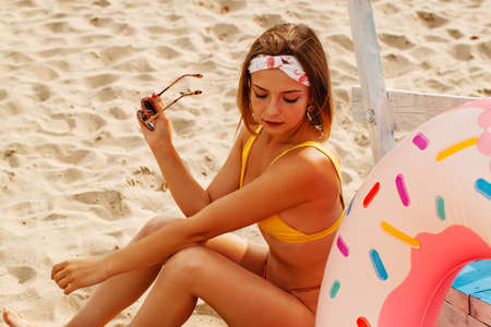 Sensual Pretty Blonde Girl In Swimsuit Lying On White Sand At Beach