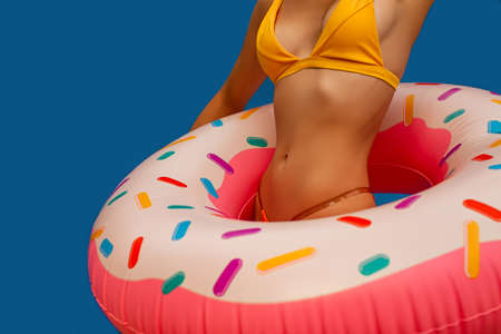 Young Woman Girl Posing With Donut-Shaped Swim Inflatable Ring Isolated On Blue Background.の写真素材
