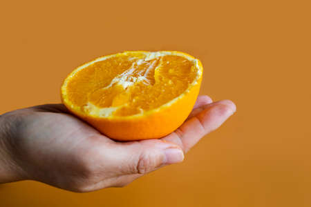 Woman's Hands Holding Halves Of Orange On Yellow Orange Background.の写真素材