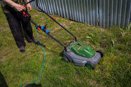 Man Cutting Green Grass With Lawn Mower In Backyard. Gardening Country Lifestyle.