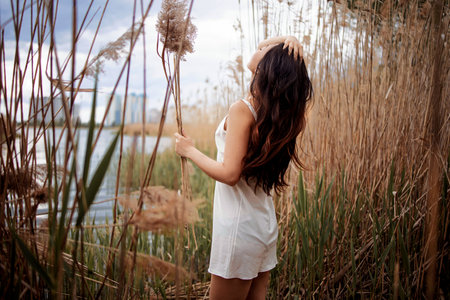 Beautiful Woman With Long Hair In Dress Near The Lake In The Reedsの写真素材