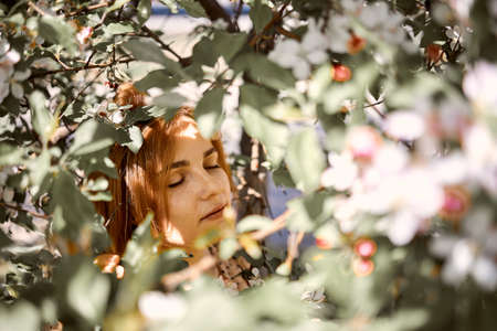 Portrait Of A Young Beautiful red Head Woman With Shadows From Trees On Faceの写真素材