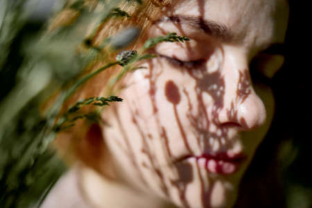 Portrait Of A Young Beautiful red Head Woman With Shadows From Trees On Faceの写真素材