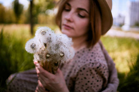 Charming Sensual Young Woman Sitting On Grass With Dandelionsの写真素材