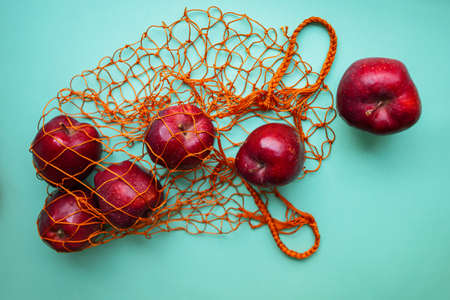 Mesh Shopping Bag With Red Apples On Blue Background.の写真素材