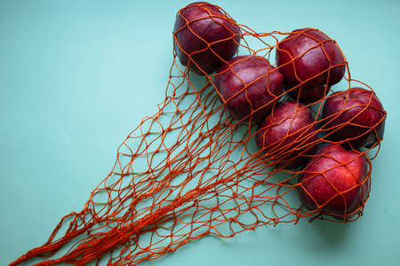 Mesh Shopping Bag With Red Apples On Blue Background.の写真素材