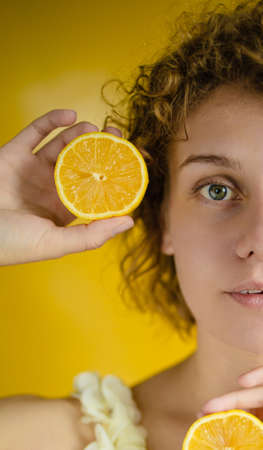 Headshot Of Beautiful Blonde Woman Holds Juicy Lemon Slices Has Healthy Shinyの写真素材