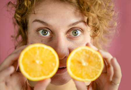 Headshot Of Beautiful Blonde Woman Holds Juicy Lemon Slices Has Healthy Shinyの写真素材