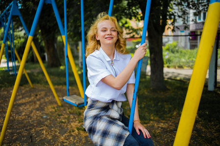 Happy Healthy Teenager Girl Wear Casual Cloth Smile Sitting Play Swing In The Parkの写真素材