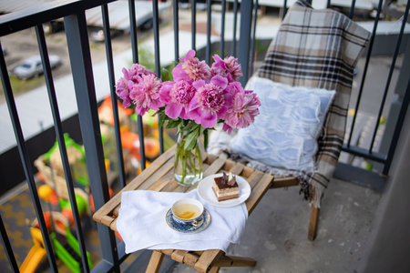 Bouquet Of Peony Flowers, Cup Of Tea And Cake On Wooden Table on the balcony.の写真素材