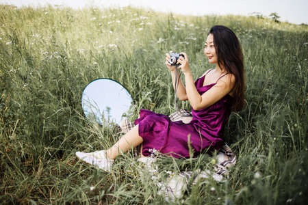Pretty Asian Woman Holds An Old Camera In Green Field.の写真素材