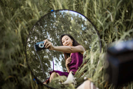 Woman Holds Camera Against A Mirror In Green Field.の写真素材