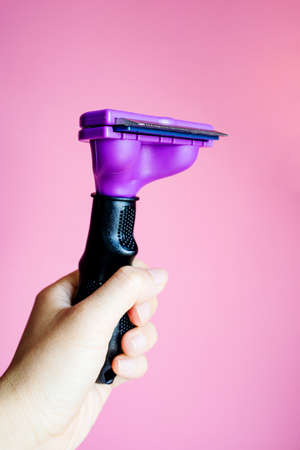 Hand Holding Comb For Grooming Pet On Pink Background, Copy Space.