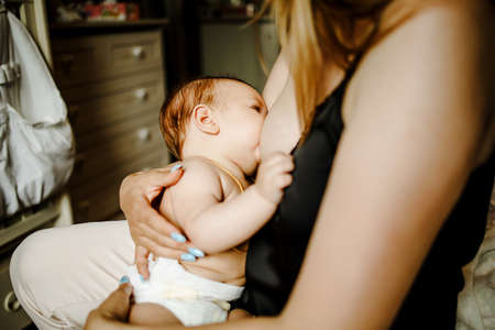 Caucasian Mother Breastfeeding Baby Son On Sofaの写真素材
