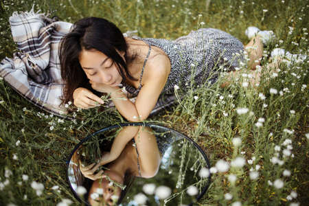Portrait Of Pretty Young Romantic Asian Woman Sitting In Chamomile Flower Field