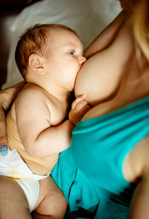 Caucasian Mother Breastfeeding Baby Son On Sofaの写真素材