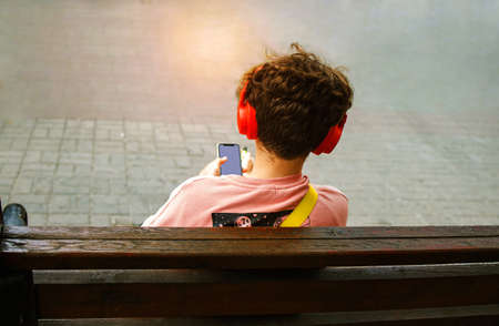 Male Teenager With Mobile Phone And Headphones In The City