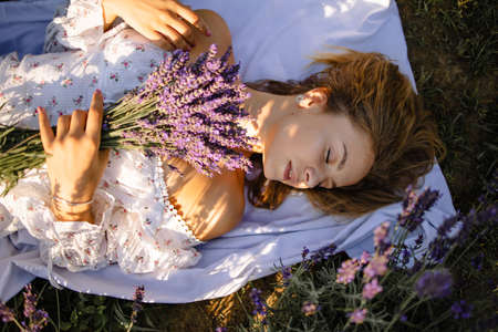 Young Woman In Hat Lying In Lavender Field On Summer Dayの写真素材
